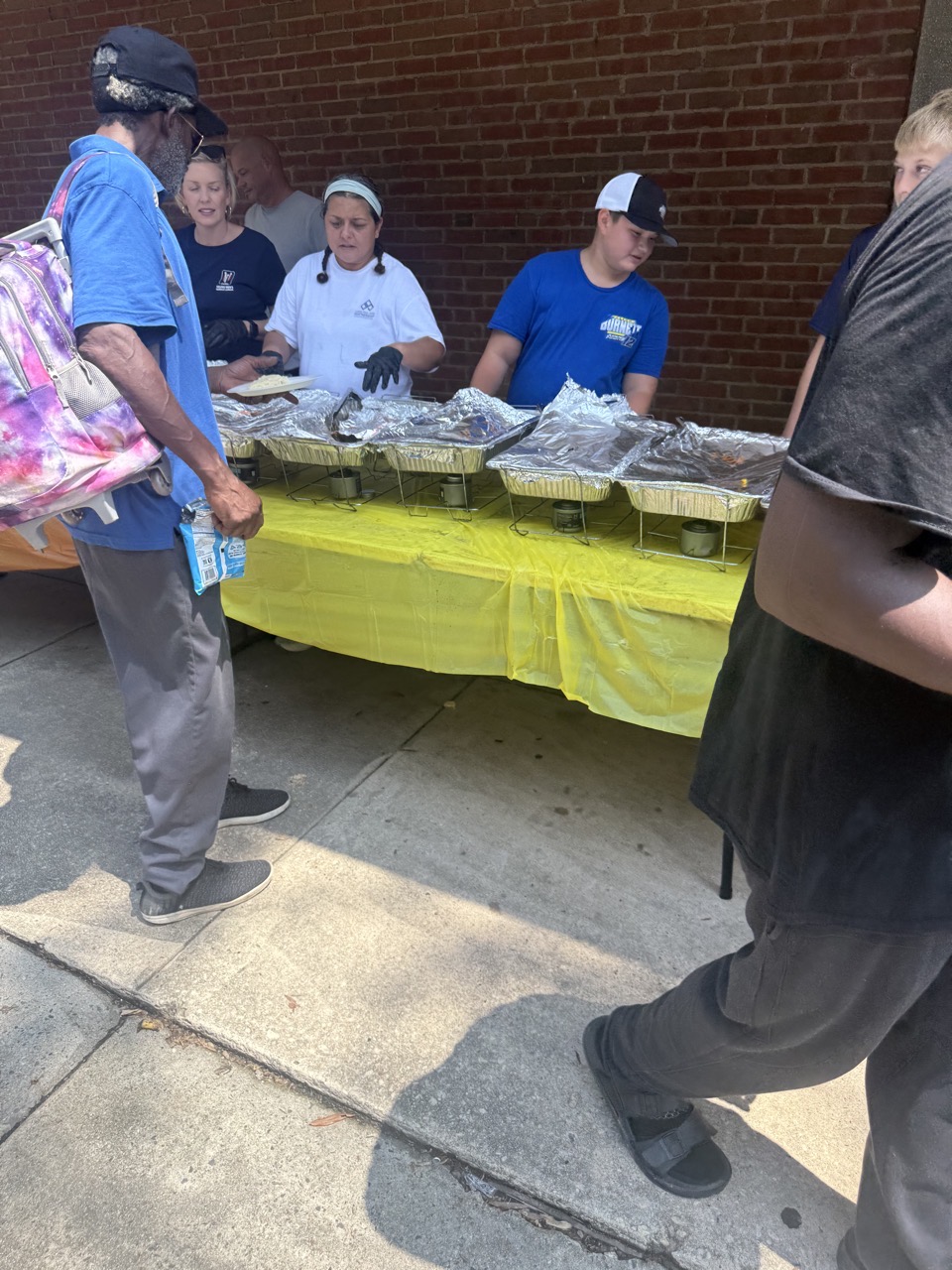 Jaxon and fellow volunteers serving meals at an outdoor University Soup Kitchen table