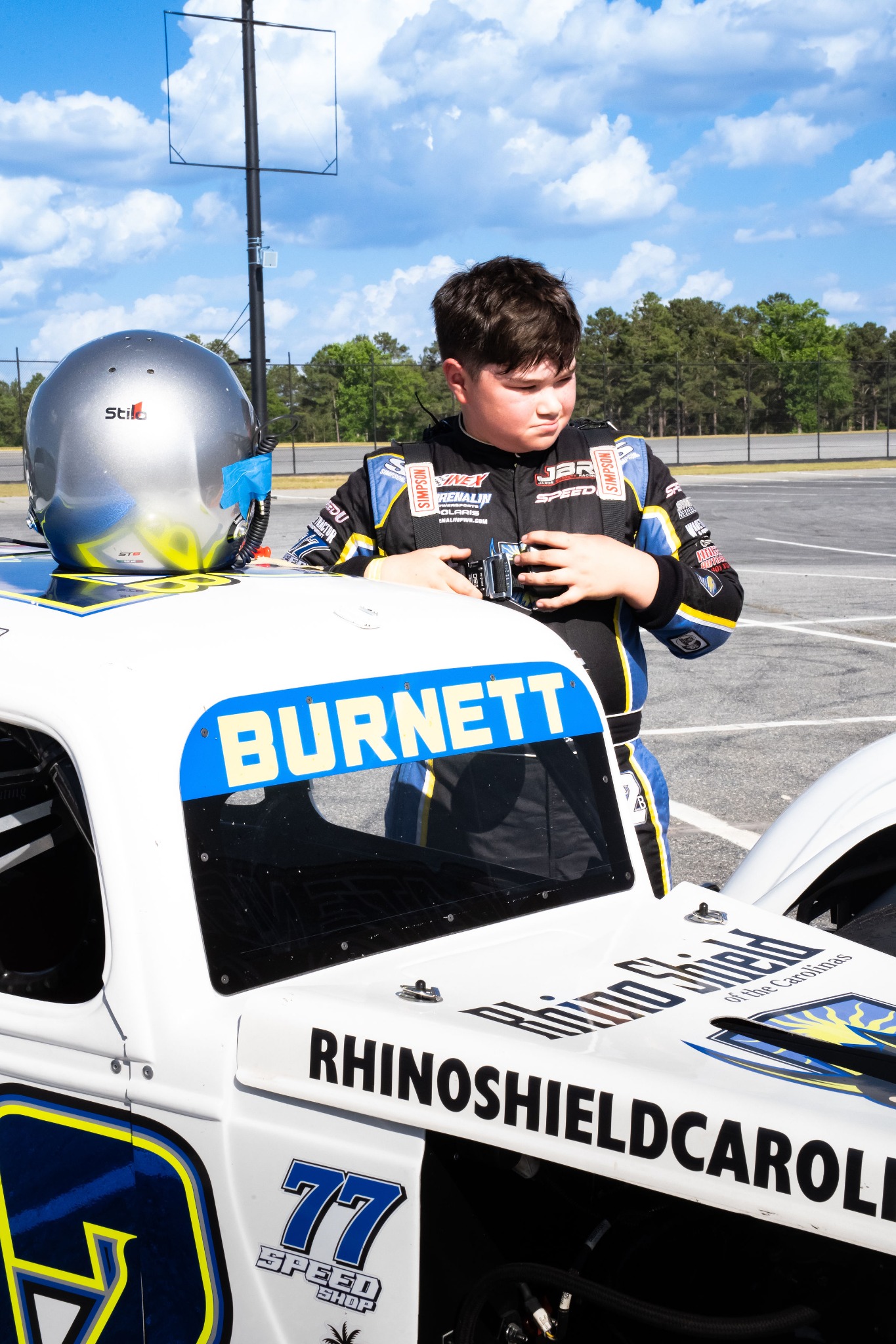 Jaxon in his racing suit beside his Legend car