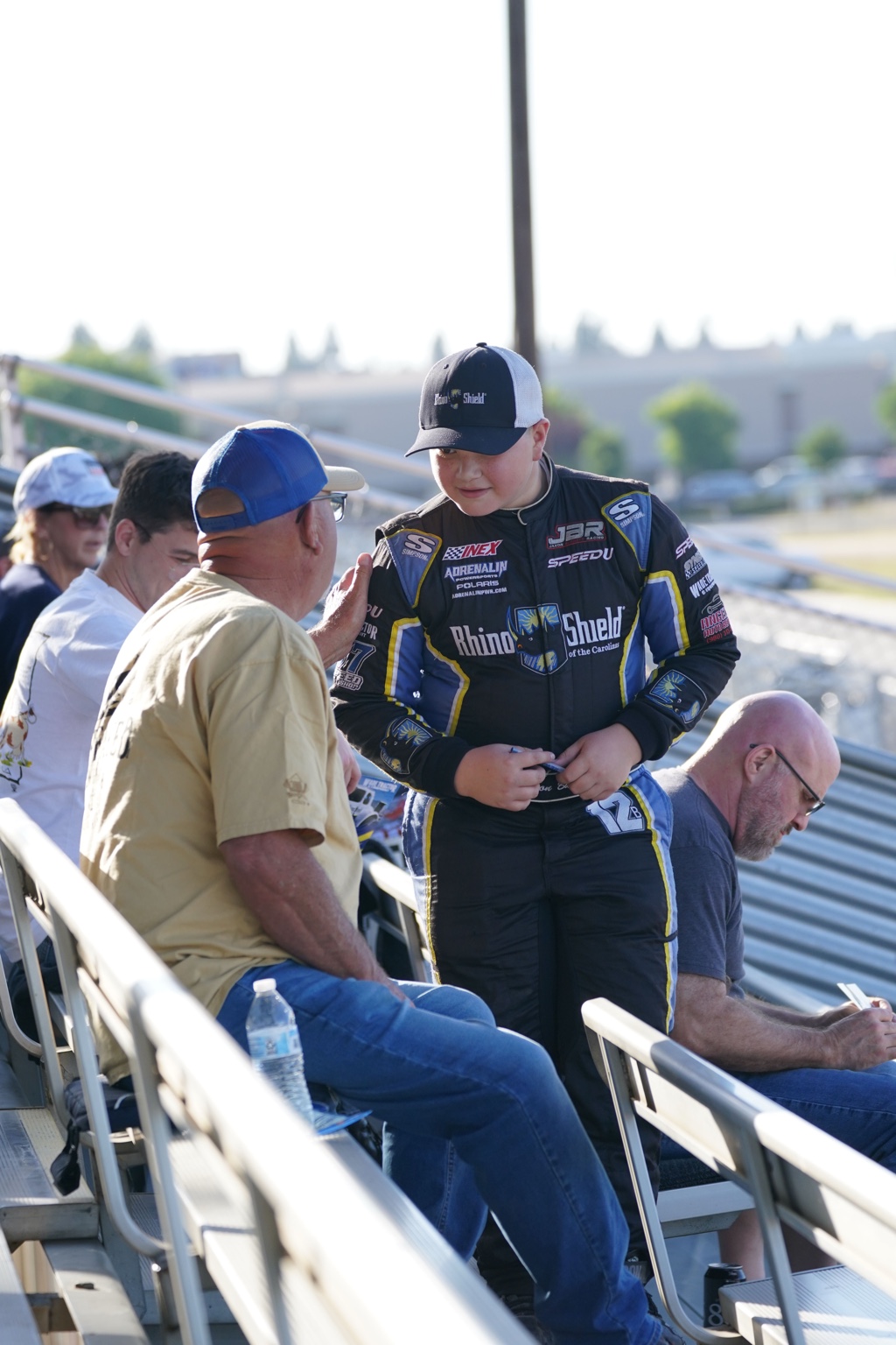 Jaxon in his racing suit talking with fans in the grandstands